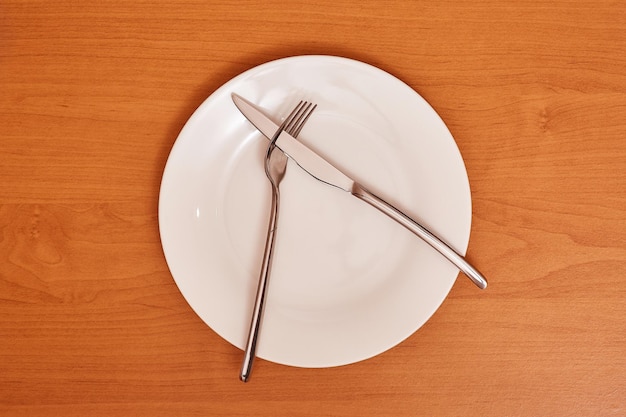 A signal didn't like the dish empty and clean blue plate with fork and knife on a wooden table as an example of table etiquette