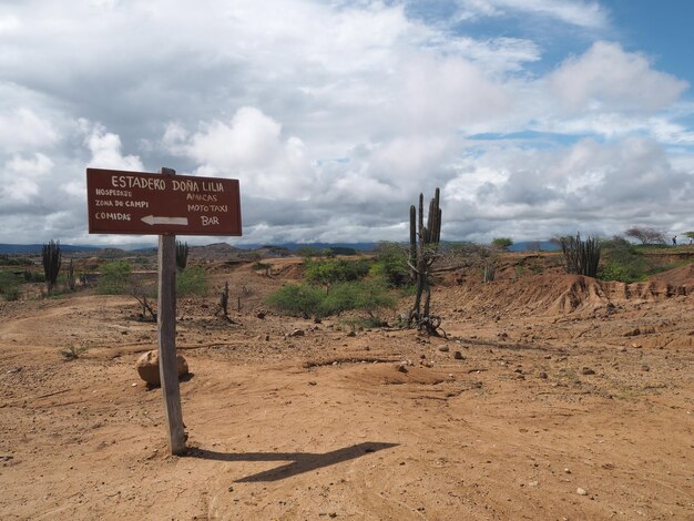 Photo signboard on field at desert against cloudy sky