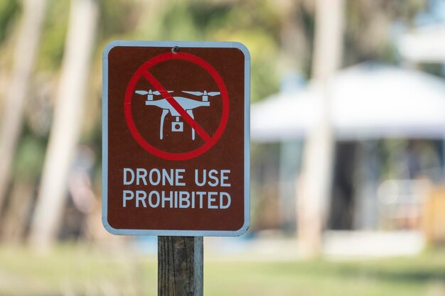 Photo signpost with warning about drone usage prohibition in state park warning notice against using uav and quadcopters