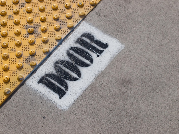 Signs for light rail train door location painted on the asphalt in Denver, Colorado.