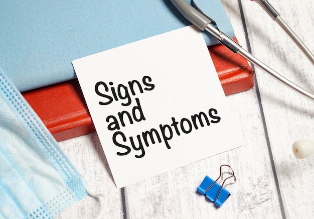 Signs and symptoms words on white sticker and stethoscope