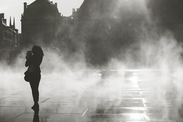 Silhoette of woman taking picture on water mirror in Bordeaux, France