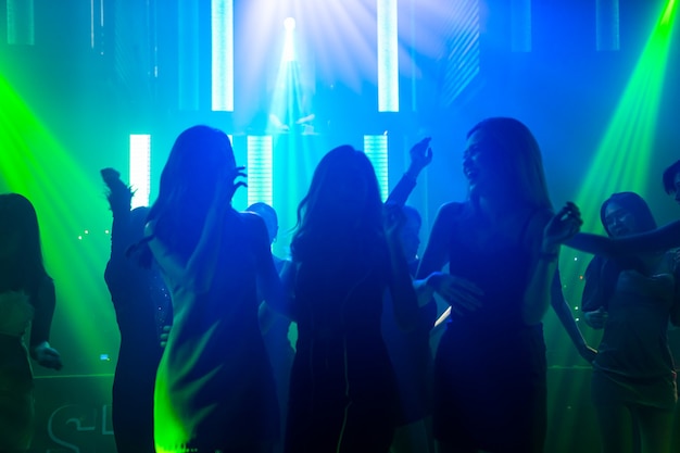 Silhouet afbeelding van mensen dansen in disco nachtclub op muziek van Dj op het podium