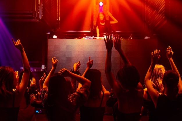 Silhouet afbeelding van mensen dansen in disco nachtclub op muziek van Dj op het podium