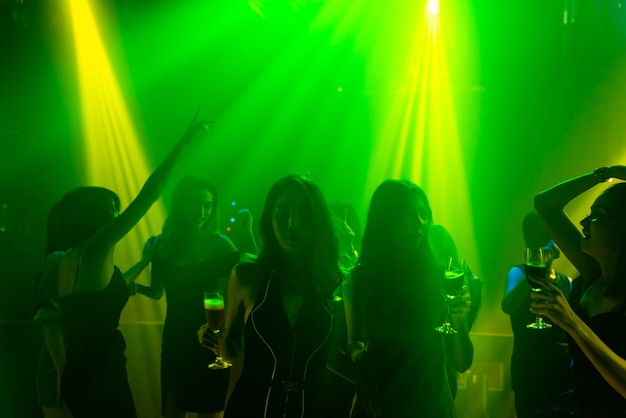 Silhouet afbeelding van mensen dansen in disco nachtclub op muziek van Dj op het podium