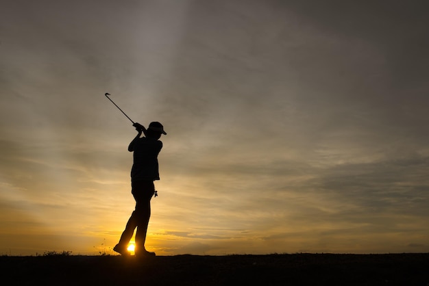 Silhouet Aziatische golfspeler golfen tijdens prachtige zonsondergang