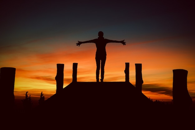 Silhouet aziatische vrouw die met handen omhoog staat en een uitzicht op de hemel bereikt meisje verwelkomt een zon