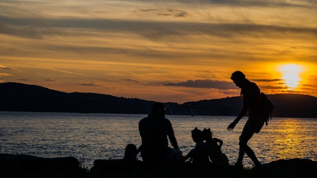 Silhouet familie tegenover rivier bij zonsondergang