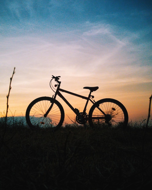 Silhouet fiets op het veld tegen de lucht