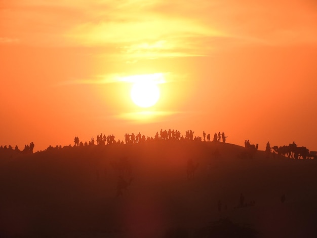 Silhouet groep mensen in de woestijn tegen oranje lucht