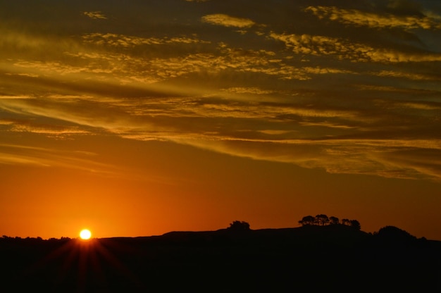 Silhouet heuvel tegen bewolkte lucht tijdens zonsondergang