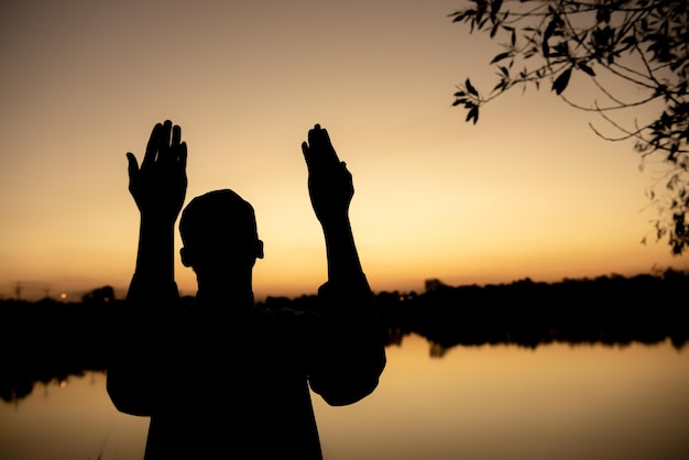 Foto silhouet jonge aziatische moslim man bidden op sunsetramadan festival concept