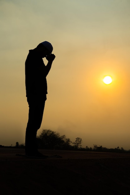 Silhouet jonge Aziatische moslim man bidden op sunsetRamadan festival concept