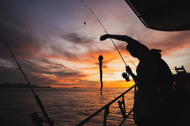 Silhouet jonge man vissen in open zee vanaf de boot