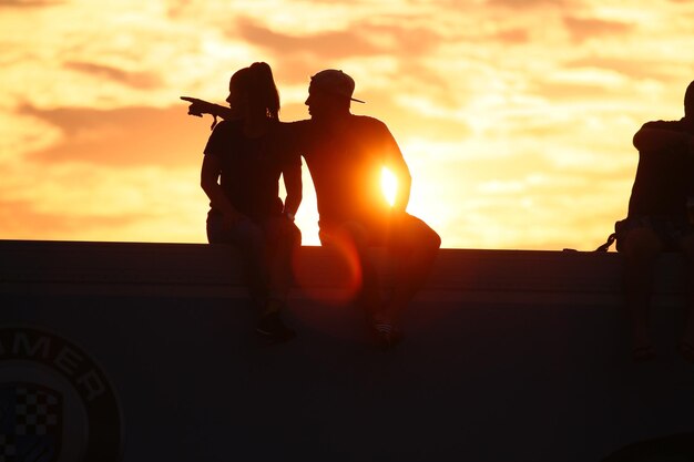 Foto silhouet koppel zit tegen de oranje hemel