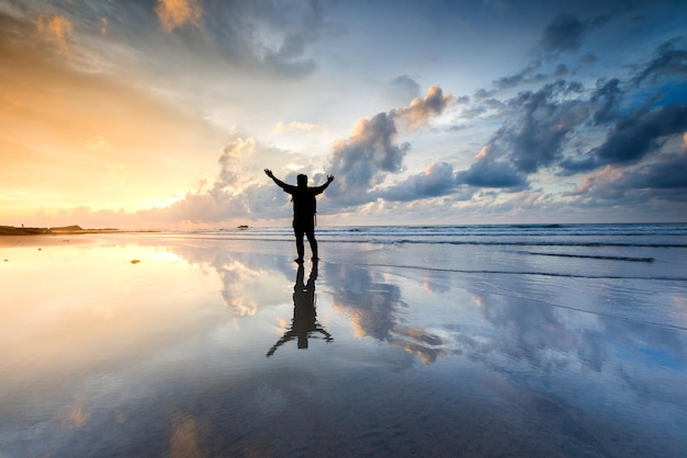 Silhouet man die op het strand staat tegen de hemel tijdens de zonsondergang