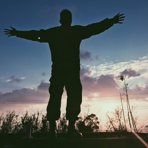 Foto silhouet man die tegen de hemel staat bij zonsondergang