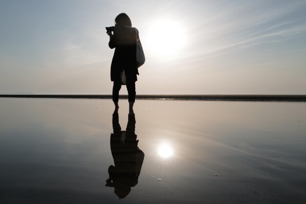 Foto silhouet man die tijdens de zonsondergang in de zee tegen de lucht staat