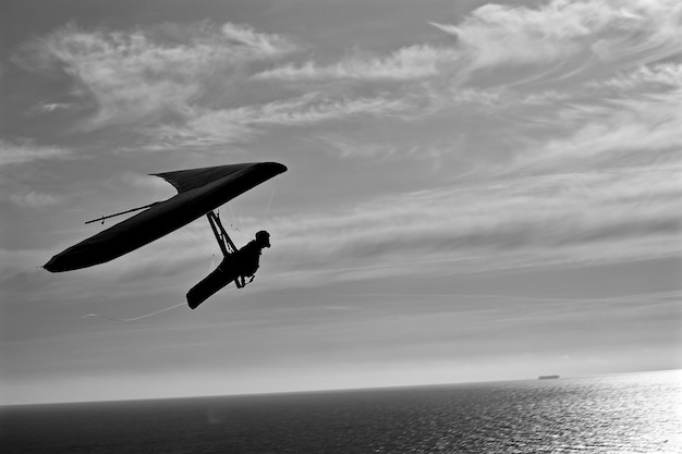 Foto silhouet man hang-gliding boven de zee