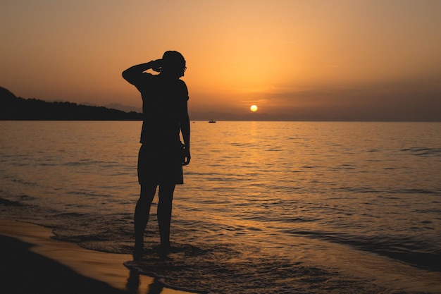 Silhouet man op het strand tegen de hemel tijdens zonsondergang