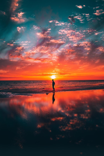 Silhouet man op het strand tegen de hemel tijdens zonsondergang