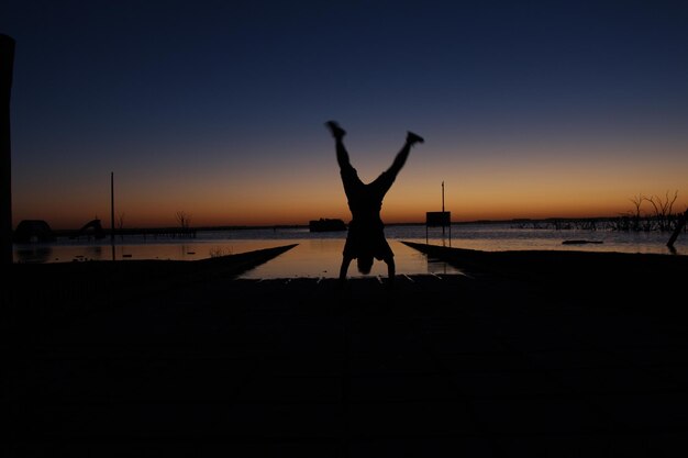 Foto silhouet man op het strand tegen een heldere lucht bij zonsondergang