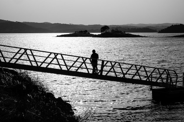 Silhouet man op reling door de zee tegen de lucht