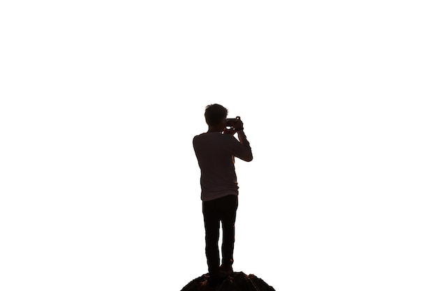 Foto silhouet man reiziger staande met het nemen van foto's van retro camera op rots geïsoleerd op witte achtergrond