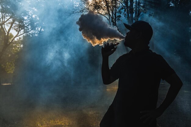 Silhouet man rookt elektrische sigaret in het bos