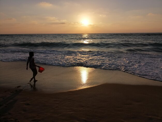 Foto silhouet meisje op het strand tegen de hemel tijdens de zonsondergang