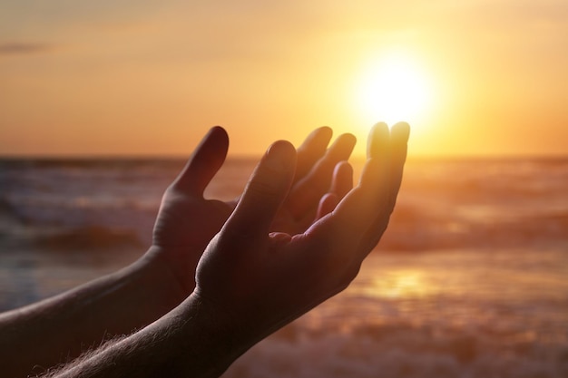 Silhouet menselijke handen openen palm op sunset beach. Christelijk biddend concept