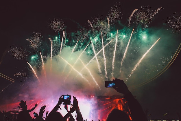 Silhouet mensen fotograferen vuurwerk tegen de hemel's nachts