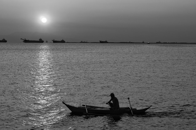 Silhouet mensen in een boot op zee tegen de hemel tijdens de zonsondergang