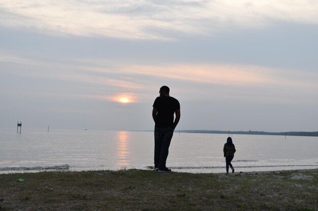 Foto silhouet mensen op het strand tegen de hemel tijdens de zonsondergang