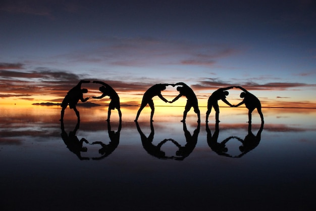 Foto silhouet mensen op het strand tegen de hemel tijdens de zonsondergang