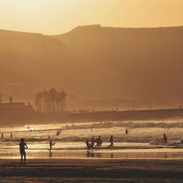 Foto silhouet mensen op het strand tegen een heldere lucht