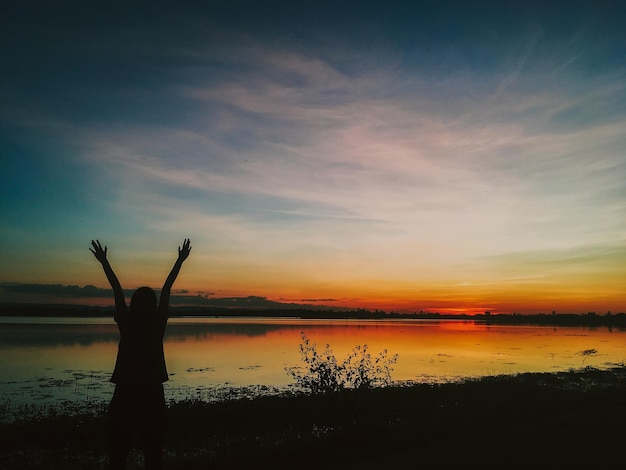 Foto silhouet persoon die bij het meer staat tegen de hemel tijdens de zonsondergang