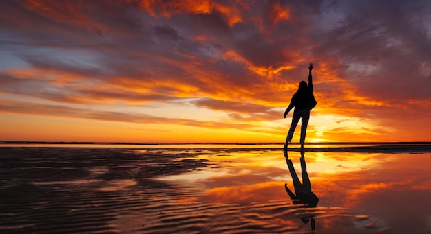 Foto silhouet persoon tegen achtergrond prachtige zonsondergang hemel op oceaan reflectie stralen zon in het water