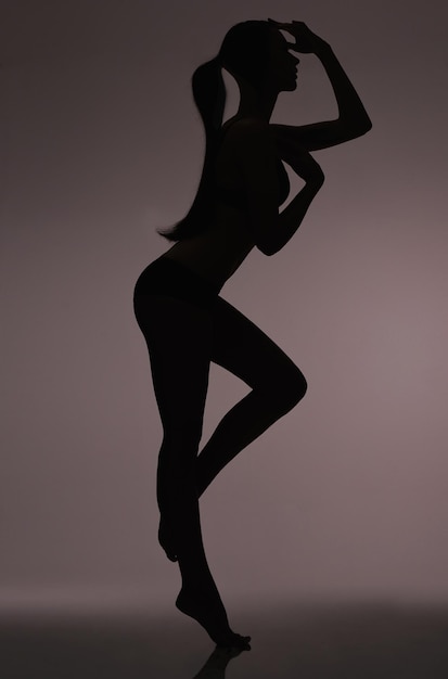 Silhouet schoonheid Studio silhouet van een mooie vrouw in lingerie tegen een grijze achtergrond