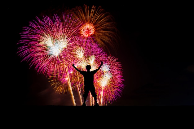 Silhouet succesvolle man op het hoogtepunt, mooie kleurrijke vuurwerk op het strand.