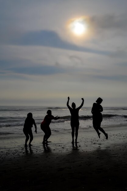 Silhouet van 4 vrouwen die bij zonsondergang op een strand springen