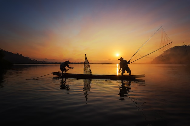 Silhouet van Aziatische visser op houten boot