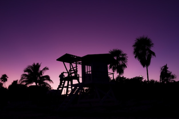 Silhouet van baywatch-toren en palmbomen bij zonsondergang in Playa del Carmen Mexico Lifeguard-concept