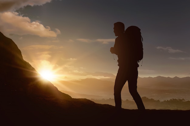 Silhouet van de backpackermens die de berg wandelen