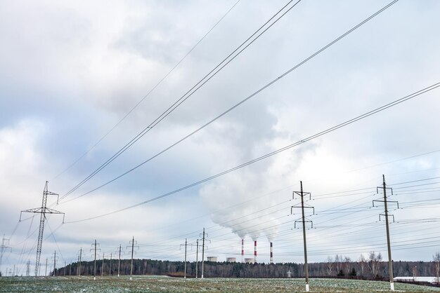 Silhouet van de elektrische hoogspanningsmasten op de achtergrond van prachtige wolken die pijpen van een thermische elektriciteitscentrale stomen