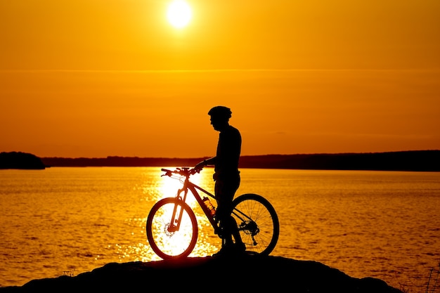 Silhouet van de fietser die bij zonsondergang op een sportfiets rijdt. Actief levensstijlconcept.