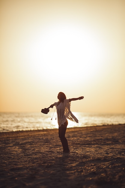 Silhouet van de vrouw met ukelele op het strand zomervakantie
