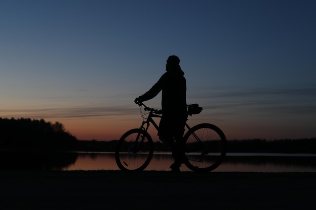 Silhouet van een fietser op het strand bij zonsondergang