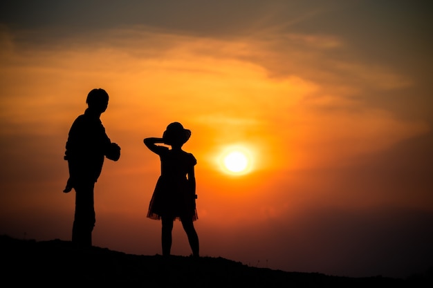 Silhouet van een gezin met een gelukkige moeder die speelt met een meisje in de avondrood