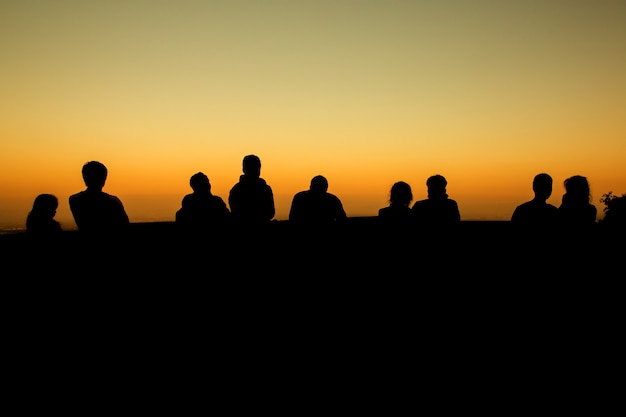 silhouet van een groep vrienden staan ​​in de zonsondergang